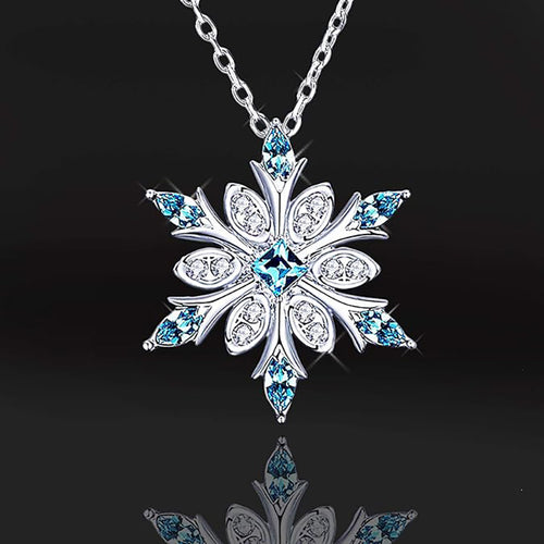 Snowflake pendant with blue center stones on black backdrop