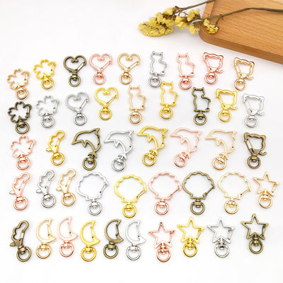 An assortment of metal outline swivel clasps in nine shapes and five color finishes is arranged on a white surface.