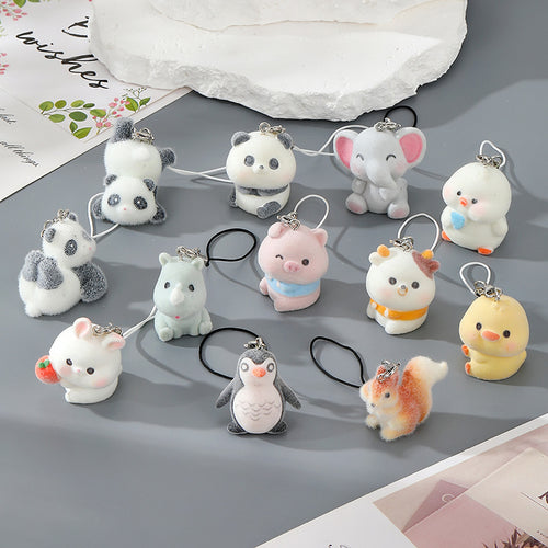 Nine flocked animal phone strap charms including pig panda elephant duck and penguin on grey surface