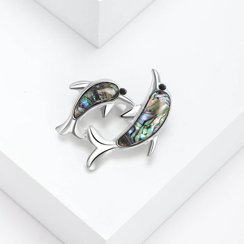 Angled display of the double dolphin brooch on a white surface
