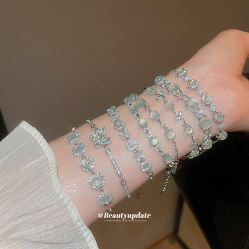 Wrist stacked with silver cat-eye and butterfly zircon bracelets