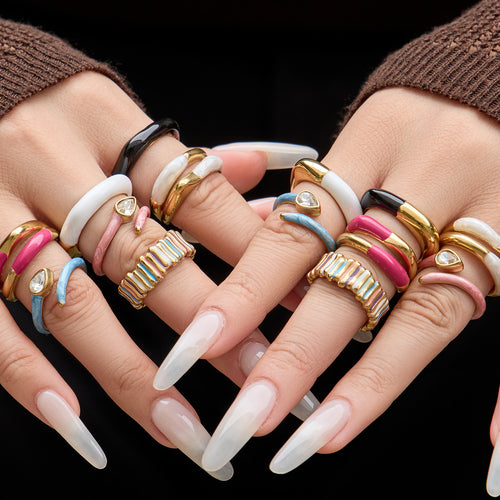 Styled hand view of colorful enamel and crystal open rings in main image 1.