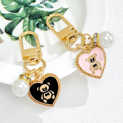 Black and pink heart charm keychains with bear silhouette cutouts shown together