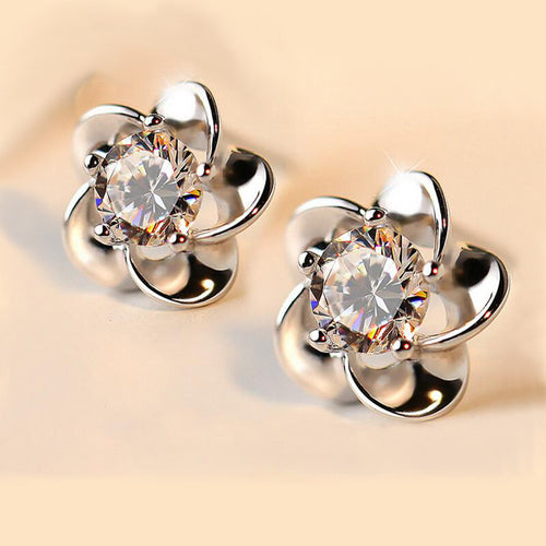 Close-up of silver flower petal studs with clear CZ centers on beige surface
