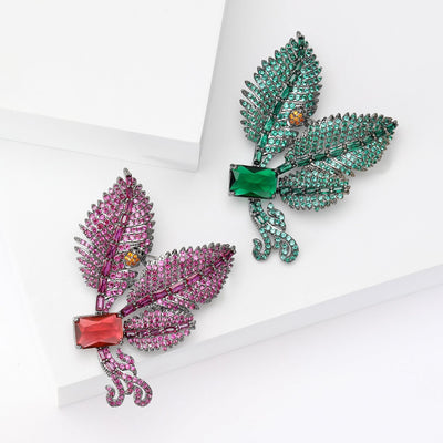 Magenta and green crystal leaf branch brooches on white steps