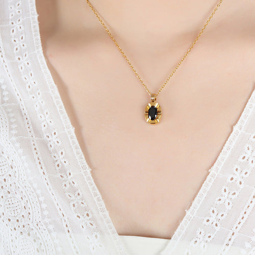 Gold oval black stone pendant necklace worn on lace top