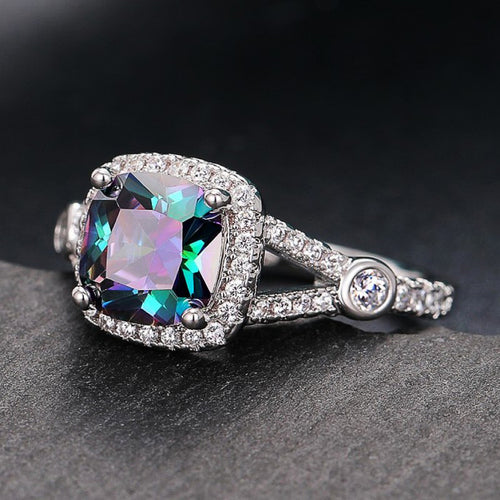 Multicolor mystic cushion halo ring angled on dark stone surface
