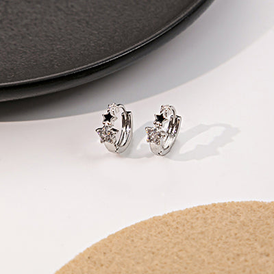 Silver star huggie hoops black enamel crystal stars on white table