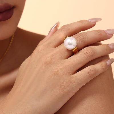 Hand wearing gold wide-band large shell pearl statement ring