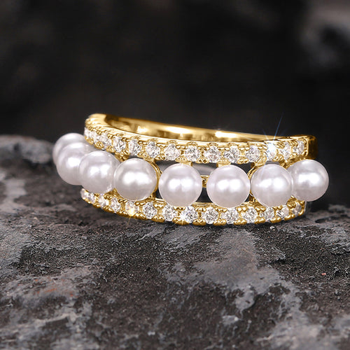 Gold pearl double crystal band ring on dark stone surface