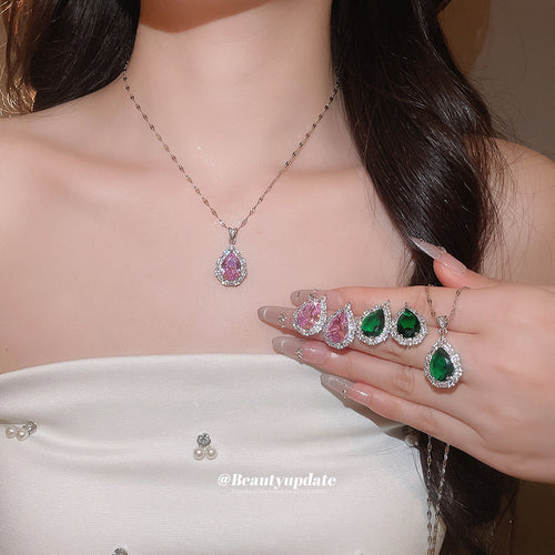 Pink teardrop necklace worn with green and pink studs and pendant held in hand