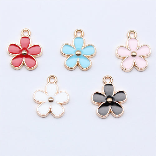 Five-petal enamel flower charms arranged on a natural wood surface