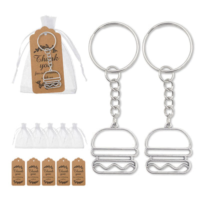 A packaged hamburger keychain beside two loose keychains, white bags and brown printed tags.