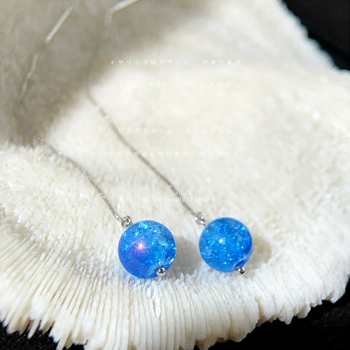 Blue crackle glass bead threaders laid on white coral texture