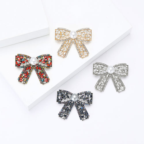 Angled display of openwork ribbon bow centered by a single white pearl-like bead