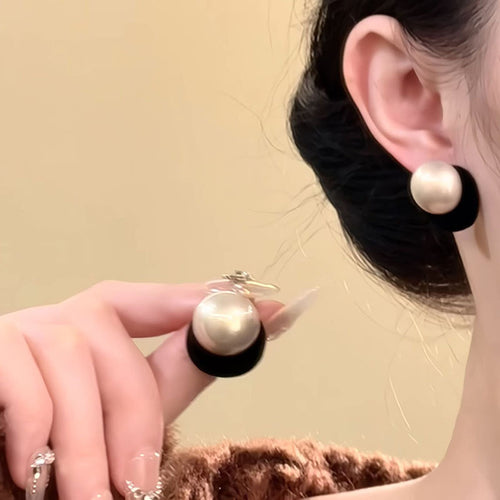 Two graduated pearl-look balls with black or red flocked surfaces shown in a styled close-up