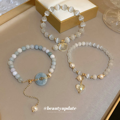 three unrelated bracelets with pale beads, heart links, and round charms shown in the first close product view