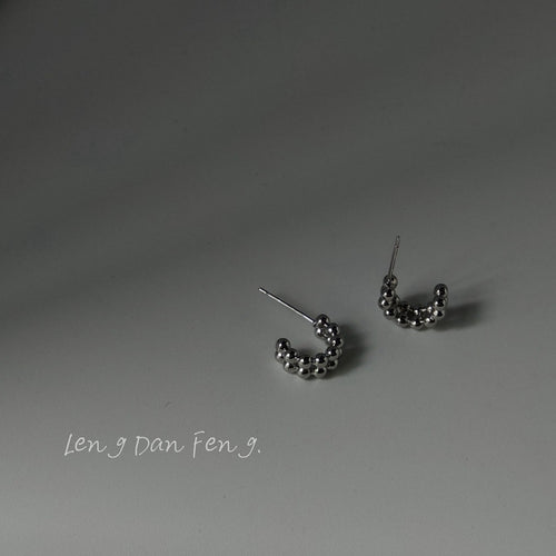 Silver beaded C mini hoops on gray surface with soft shadow