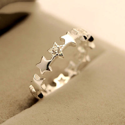 Silver star open band ring on beige jewelry cushion