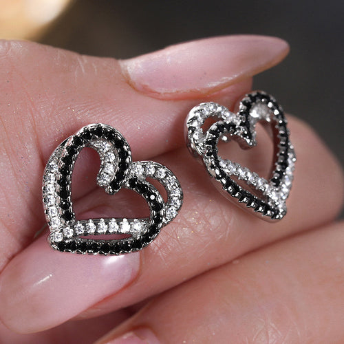Black white CZ open heart studs held in fingertips