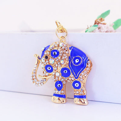 Front view of a gold-tone elephant charm with blue eye motifs and clear stones.