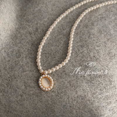 White-pearl strand gold-tone oval-halo pendant necklace laid out in full.
