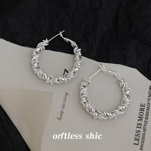 Twisted-rope large hoops in gold and silver tone displayed in silver tone.