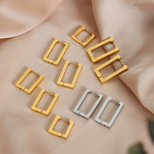 Assorted gold and steel rectangle square huggie hoops on peach fabric