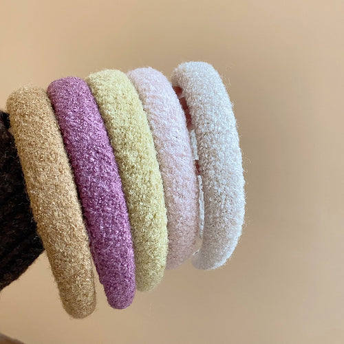 Row of fuzzy boucle headbands in camel mauve yellow blush and ivory held together