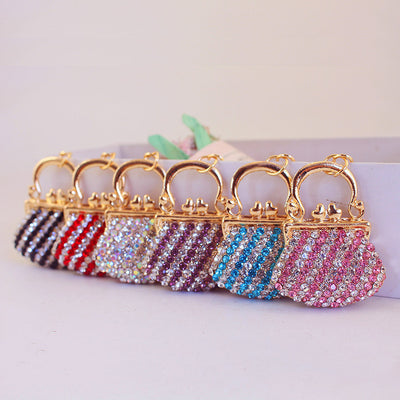 Six gold-tone purse charms display black, red, iridescent, purple, blue, and pink rhinestone patterns.