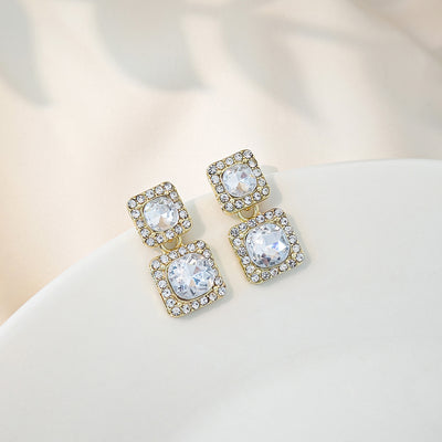 Gold double square crystal dangle earrings on white curved surface