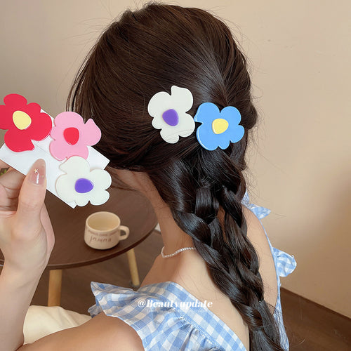 White and blue flower clips worn in braid with pink and magenta clips held on card