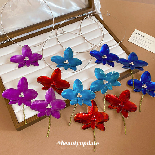 Assorted enamel orchid earrings and wire chokers in jewelry box tray