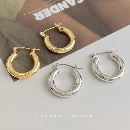 Gold and silver tube hoops laid on magazine and white table