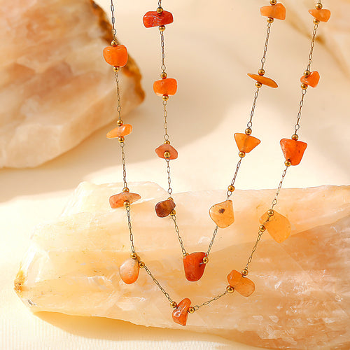 Close-up orange natural stone chips on gold chain over rock