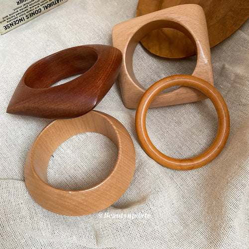 Four wooden bangles in round and square shapes on linen cloth