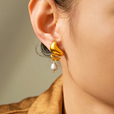 Model ear wearing gold spiral wave earring with pearl drop