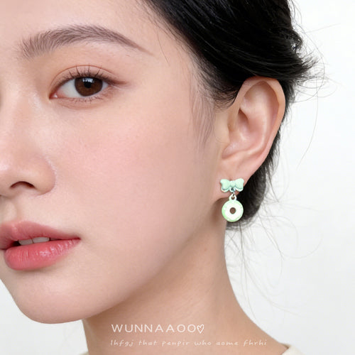 Model wearing mint green bow donut drop earring on ear