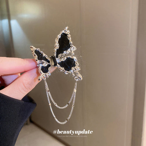 black butterfly brooch with bright silver-tone edging and two chains shown in the first close product view