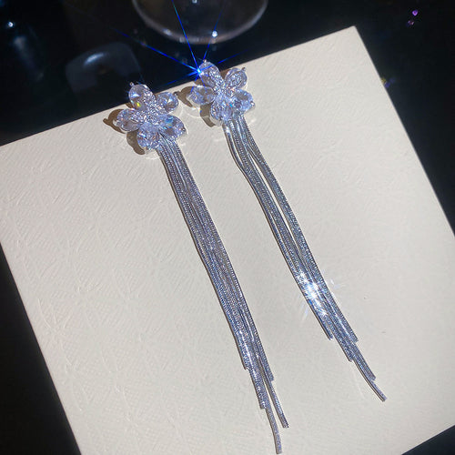 Styled view of crystal flower stud earrings with long silver and gold tassels
