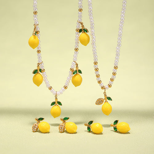 Lemon pearl necklaces and studs arranged on green background
