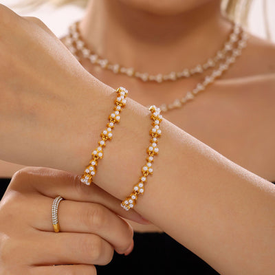 Two gold shell pearl clover bracelets stacked on wrist