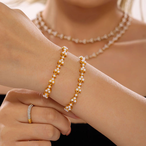 Two gold shell pearl clover bracelets stacked on wrist