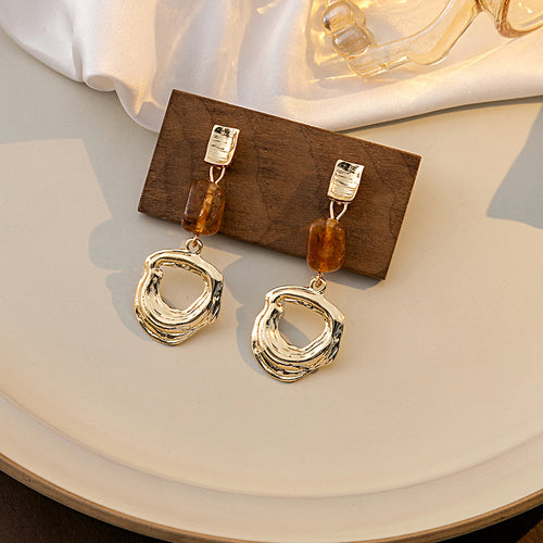 Gold open circle drops with amber brown beads on wood block plate