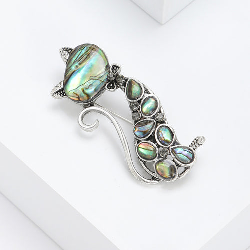 Angled display of slender seated cat filled with iridescent teardrop inlays