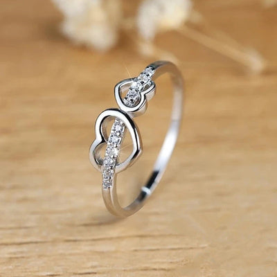 Silver double heart ring standing on light wood surface