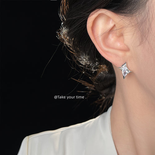 Silver star crystal stud worn on ear against dark hair