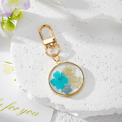Teal pressed flower cluster resin keychain with cream fillers and gold clasp