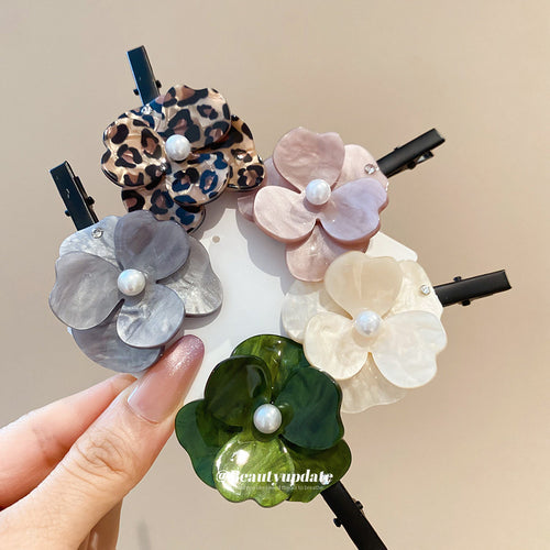 Hand holding five resin flower pearl duckbill clips in assorted colors