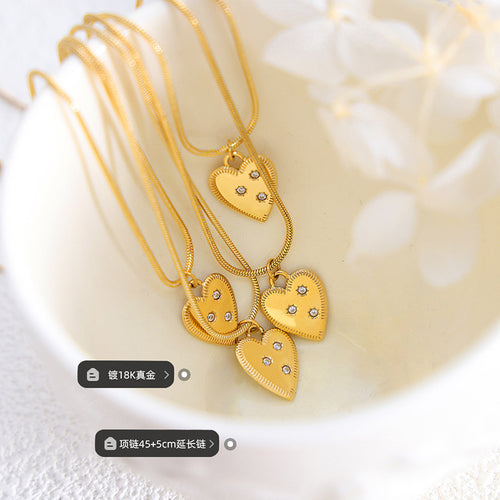 Multiple gold heart pendants on snake chains in white bowl with length labels
